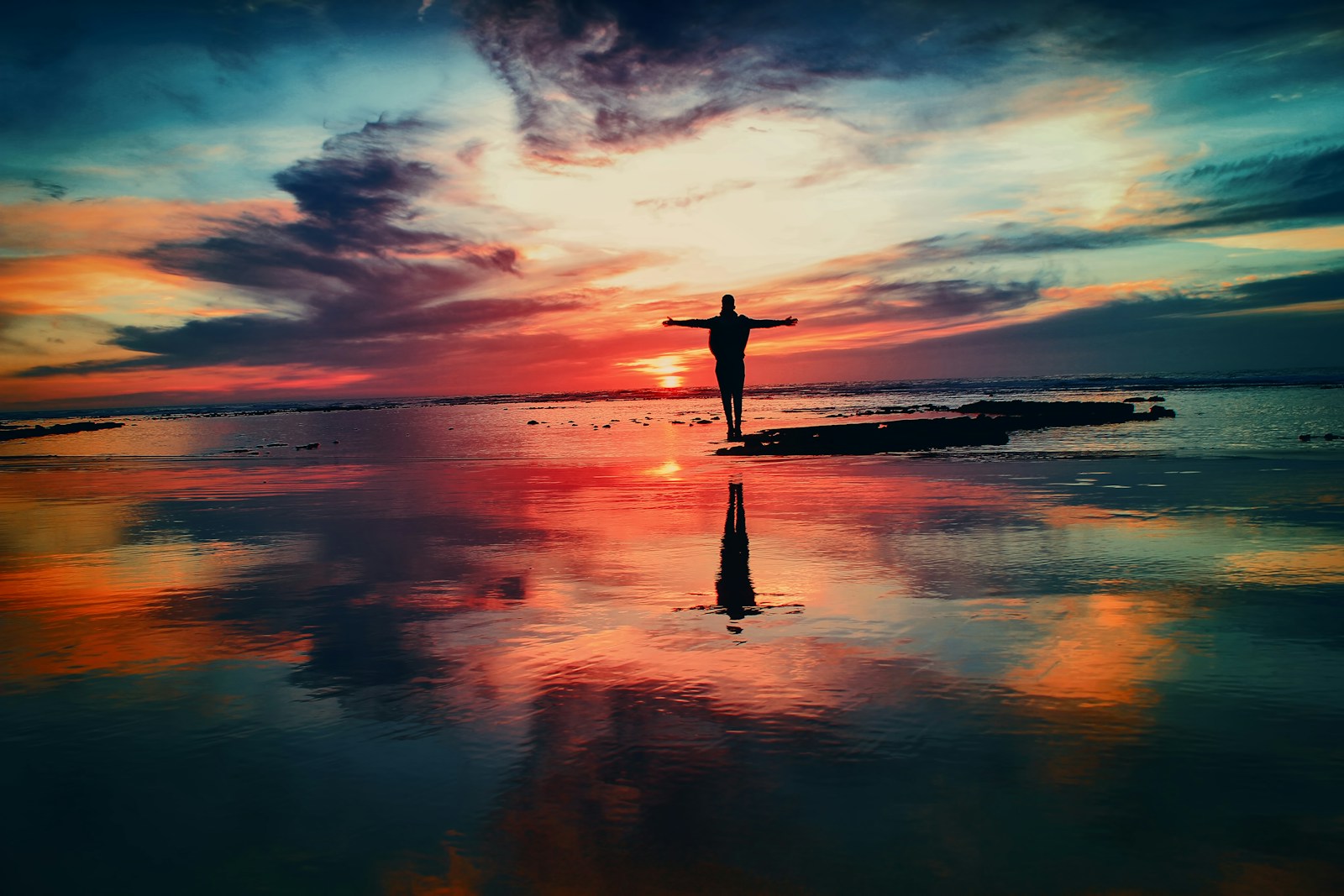 silhouette of person standing on rock surrounded by body of water, life